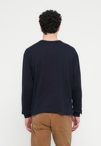 Μπλε κοντομάνικο μπλουζάκι με στρογγυλή λαιμόκοψη και άνετη εφαρμογή, κατασκευασμένο από μαλακό ύφασμα, με ριμπ μανσέτες και λεία υφή.