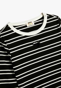 Sort og hvid stribet ribbet t-shirt med rund halsudskæring og hjerteformet udsnit i midten. Fremstillet af bomuldsstof.