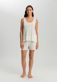 Top bianco senza maniche con scollo a barca, design a strati e orlo grezzo, abbinato a pantaloni corti coordinati, il tutto realizzato in un tessuto morbido e leggero.