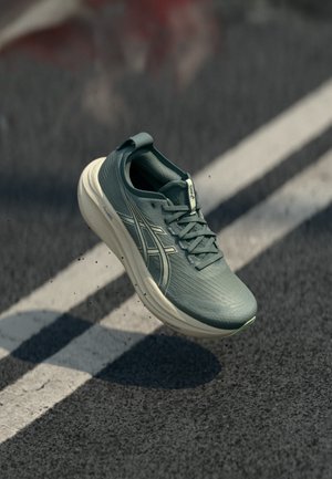 Zapatilla de running en un tono verde azul claro con parte superior texturizada, mediopié blanco y suela gris. Presenta un sistema de cordones y una lengüeta elevada en el talón.
