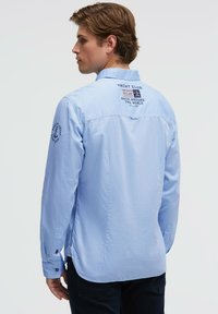 Hellblaues Langarmhemd mit besticktem "Yacht Club"-Design auf dem Rücken, geknöpften Manschetten und feiner Struktur im gesamten Stoff.