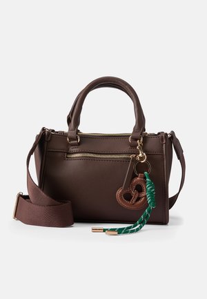 Bruine leren handtas met dubbele handvatten, een afneembare bruine schouderriem, gouden ritsen en een pretzelvormige charme met een groen en witte kwast.