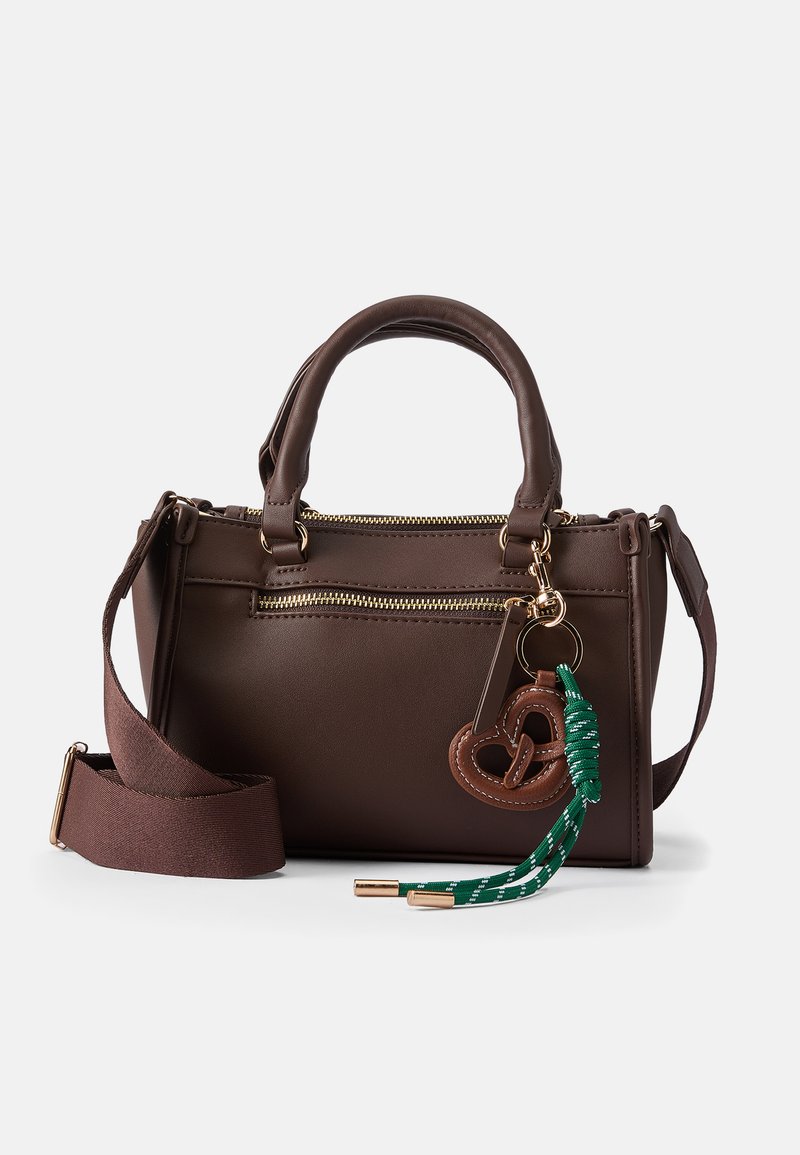 Hnedá kožená kabelka s dvojitými uchami, odnímateľným hnedým ramenným popruhom, zlatými zipsami a kúskom charm v tvare preclíka s zeleno-bielou strapcami.