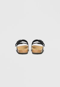 Μαύρα σανδάλια με πάτο από φελλό, ανοιχτή πλάτη, δύο λουράκια και διακοσμητικό λεπτομέρεια με λουλούδια. Υλικό με υφή που υποστηρίζει την αναπνοή.