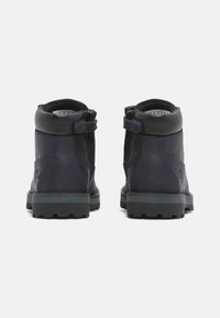 Botas de senderismo de cuero azul oscuro con una textura suave, tobillo reforzado y suela de goma negra que muestra patrones de tracción. Cierre con cremallera y correa.