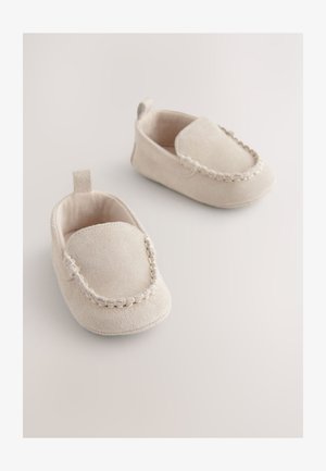 Bež velur otroški copati na potisk z mehko teksturo, z všitim poudarkom okoli odprtine in majhno zanko na peti za enostavno obuvanje.