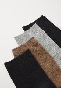 Rippensocken in vier Farben: Schwarz, Dunkelbraun, Hellbraun und Grau. Weicher Stoff mit strukturiertem Finish, oben umgeschlagen für einfachen Tragekomfort.