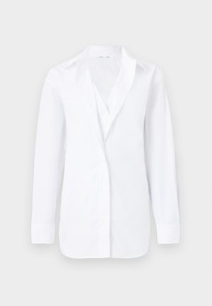 Chemise blanche à manches longues avec col et boutons, présentée à plat sur un fond clair, montrant une coupe slim et un tissu lisse.