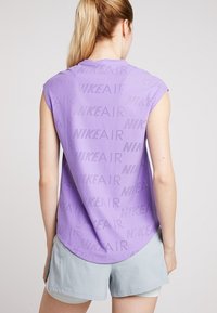 Top sin mangas de Nike en color púrpura, con un patrón perforado de "NIKE AIR". Tela ligera y transpirable, con un diseño de dobladillo redondeado.