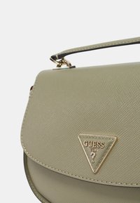 Borsa sintetica verde chiaro con finitura texturizzata, hardware dorato, dettaglio del logo triangolare e una tracolla corta.