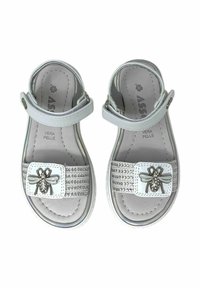 Sandali in pelle bianca con fibbia, suola piatta e motivo decorativo a forma di ape su una fascia di perline. Fodera interna di colore grigio.