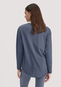Dunkelblauses Baumwollhemd mit langen Ärmeln und lockerem Schnitt, ausgestattet mit einem abgerundeten Saum und Rundhalsausschnitt, kombiniert mit passenden Leggings.