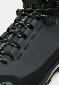 Juoda žygio bato su tekstūruotu sintetiniu viršumi, išraiškinga raištelių sistema ir ryškiu prekės ženklu; turi tvirtą gumos pado dangtį, skirtą sukibimui.