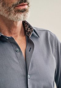 Herre skjorte i struktureret marineblåt stof, knapkrave og blomstermønster på den indre krave. Har grå knapper og en slim fit design.