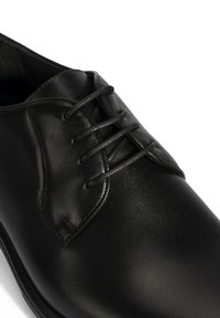 Schwarzer Lederschuh mit glatter Oberfläche, runder Zehenform und sechs Ösen für die Schnürsenkel. Das Design ist klassisch und mit minimalen Akzenten versehen.