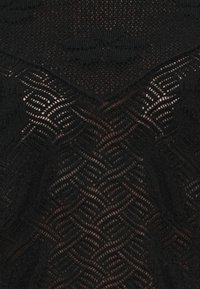 Tissu tricoté noir présentant un motif complexe de lignes ondulées, avec une texture semi-transparente et des épaisseurs de points variables sur l'ensemble.