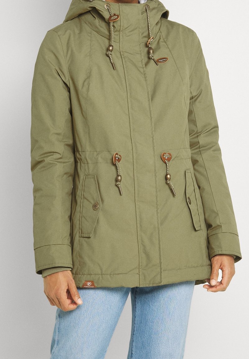 Olive green waterproof parka with a hood, drawstring closure, two front pockets, gold-tone hardware, and ribbed cuffs. Casual design.