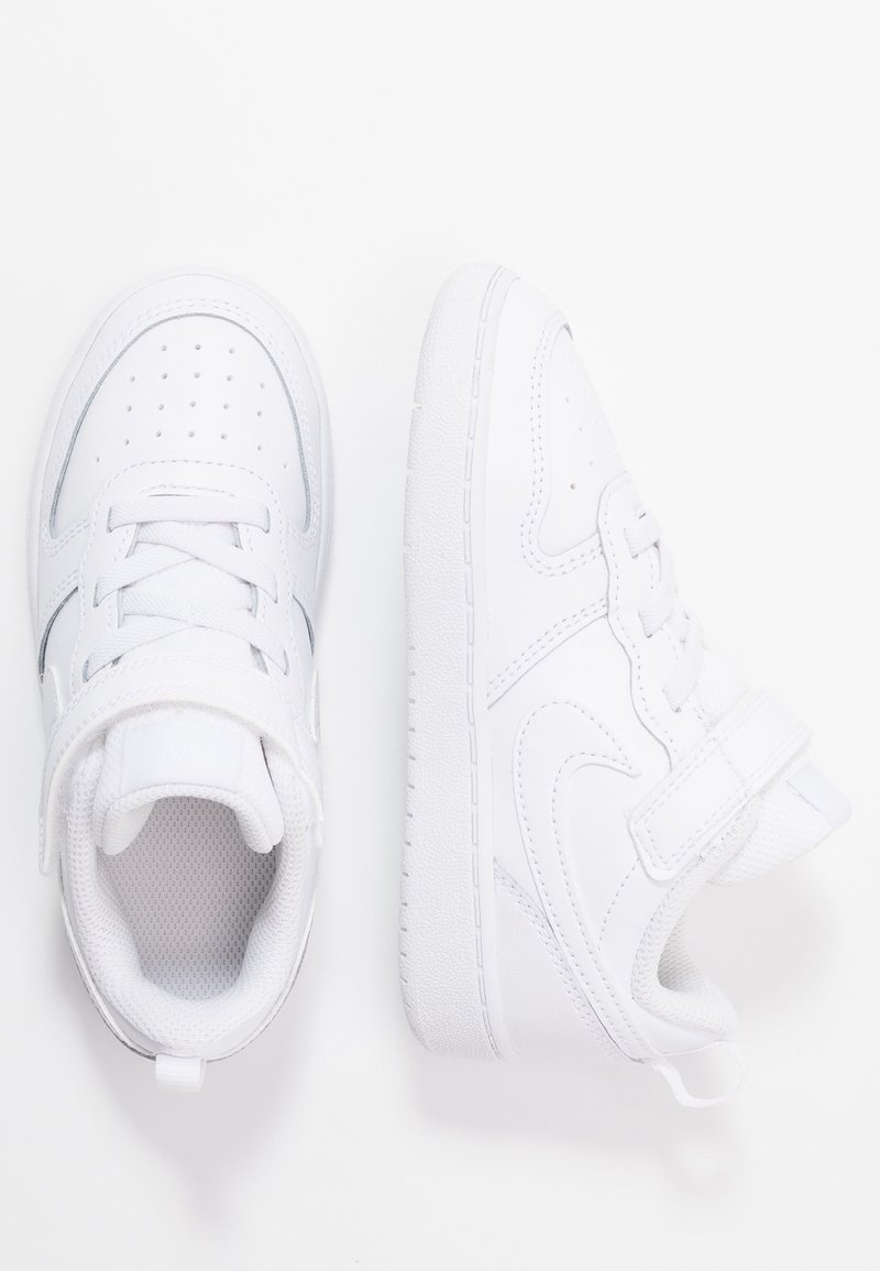 Baskets blanches avec une tige en cuir lisse, un bout perforé, une semelle en caoutchouc plate et une sangle ajustable en Velcro. Détails de conception minimalistes.