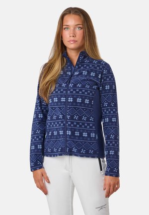 Marineblauwe fleece jack met ritssluiting, voorzien van witte geometrische en sneeuwvlokpatronen, met een hoge kraag en zijzakken met rits. Zachte textuur.