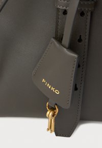 Bolsa de mão em couro cinza escuro com um detalhe em metal dourado e uma etiqueta com o nome da marca "PINKO." Textura suave e design minimalista.