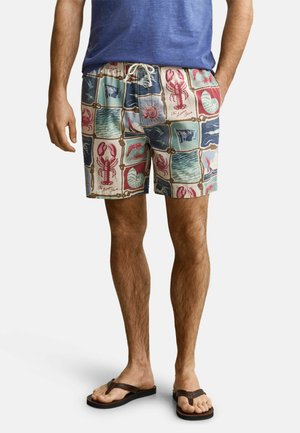 Homme portant un short de bain coloré à motifs de homard, coquillages et océan, assorti à une chemise bleue et des tongs marron.