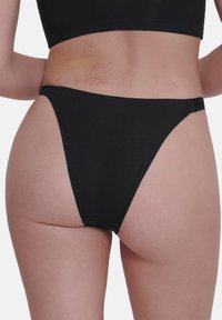 Zwarte katoenen bikini broekjes met een hoog uitgesneden ontwerp. Voorzien van naadloze randen en minimale bedekking. Textuurstof lijkt zacht en rekbaar te zijn.