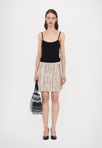 Black sleeveless top, multicolored striped skirt with buttons, and a black and white zigzag patterned tote bag. Heels complete the outfit.
