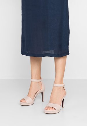 Beige sandalen met hoge hak, peep toe, enkelriem en een plateauzool. Gladde lederen textuur, slanke hak en minimalistisch ontwerp.