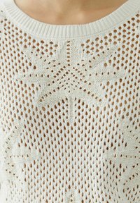 Weißer gestrickter Pullover mit lockerem, offenem Gewebe. Mit sternförmigen Mustern und einem gerippten Kragen. Leichte Textur, lässiges Design.