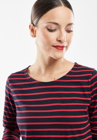 Marineblå langærmet skjorte med røde horisontale striber, der har en rund halsudskæring og blødt, strækbart stof.