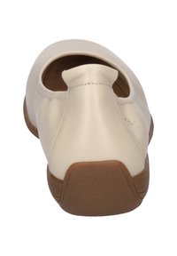Beige leather slip-on shoe with a rounded toe, open heel, and a textured brown rubber sole. Minimal design with clean lines and stitching detail.