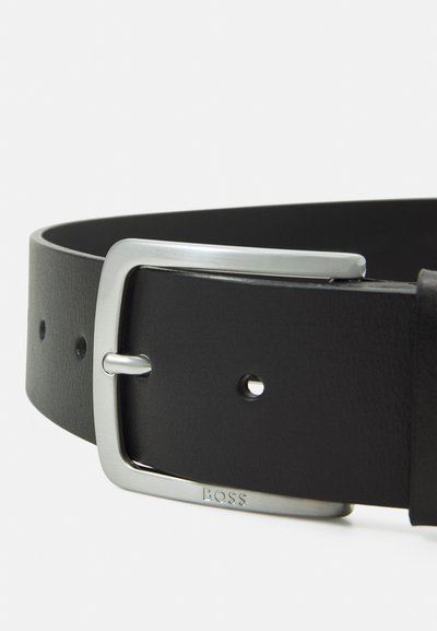 Ceinture en cuir noir avec une boucle en métal argenté rectangulaire portant le logo de la marque. Texture lisse avec plusieurs trous d'ajustement le long de la sangle.