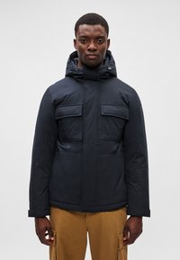 Casaco puffer azul marinho com capuz ajustável, dois bolsos no peito e punhos ajustáveis. Textura suave e material durável.