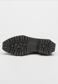 Suola di scarpa in gomma nera con un motivo di battistrada robusto, caratterizzato da scanalature triangolari e a zigzag per una migliore aderenza. Contrassegnata con "FATTO IN ITALIA" e taglia 39.