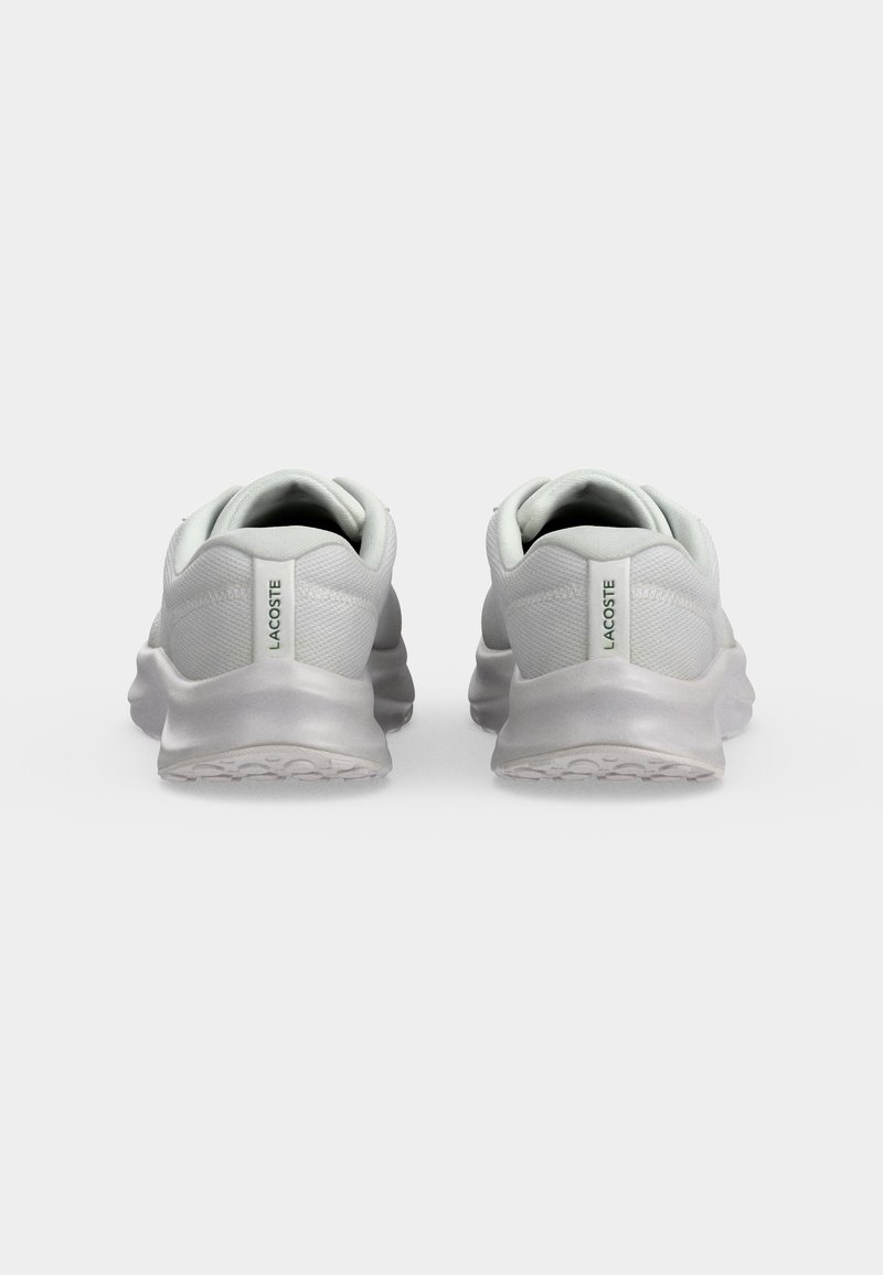 Paar weiße Lacoste-Sneaker, von hinten gezeigt, mit strukturierten Sohlen und einem vertikalen Markenetikett an jeder Ferse.