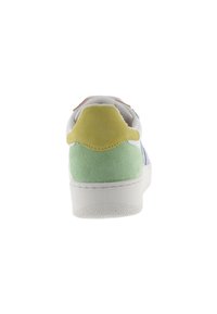 Sneaker bianco con tallone in suede verde e giallo, suola bianca, vista da dietro su uno sfondo bianco.