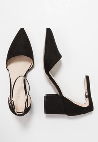 Black suede high-heeled shoes with a pointed toe, open back, and a chunky heel. Interior features a beige lining.