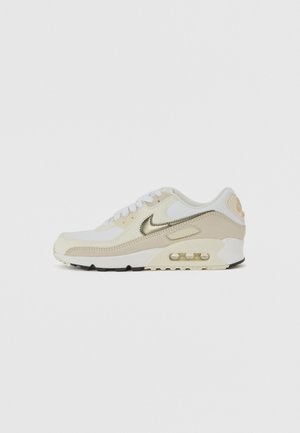White and beige Nike Air Max sneaker with metallic silver swoosh and visible air cushioning in the sole, shown from the side.