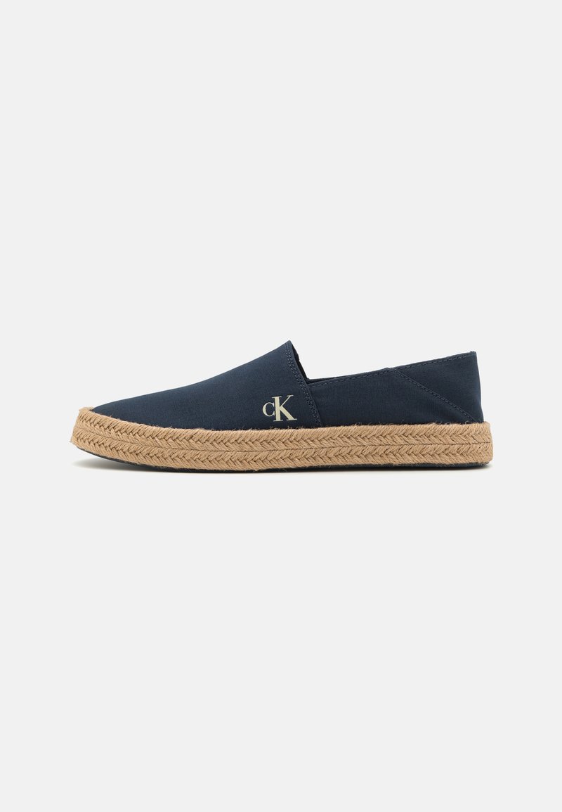 Navy cotton slip-on shoes with a braided jute sole. Features discreet CK logo on the side. Smooth surface and simple design.
