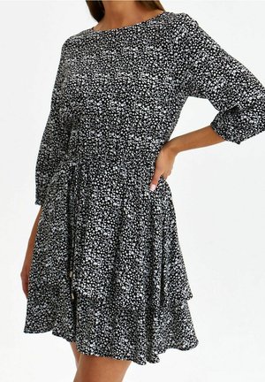 Černobílé květinové šaty s tříčtvrtečními rukávy, s sepraným pasem a vrstveným volánkovým lemem. Vyrobeno z lehkého materiálu.