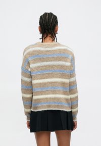 Strikket genser med løs passform og brune, beige og lyseblå striper. Teksturen virker myk og lodden, med ribbestrikkede mansjetter.