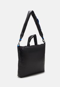 Sac matelassé noir avec sangle noire réglable et accents bleus. Comprend deux poignées et une forme rectangulaire, fabriqué en matériau lisse et durable.