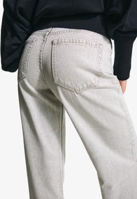 Világosszürke farmernadrág laza fit szabással, hátsó zsebekkel, látható varrással és enyhén megkopott textúrával.