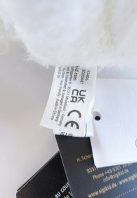Clothing label with UKCA and CE certification marks attached to white fabric and black tags with contact information.