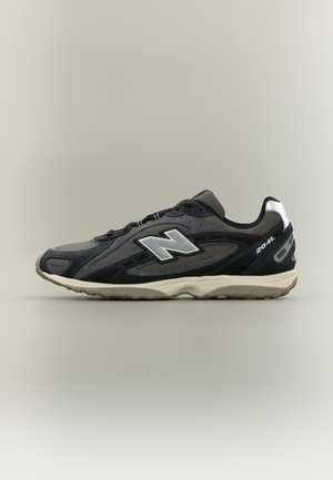 Baskets New Balance 204L gris foncé et noires avec logo blanc et semelle beige, vues de profil sur un fond clair uni.