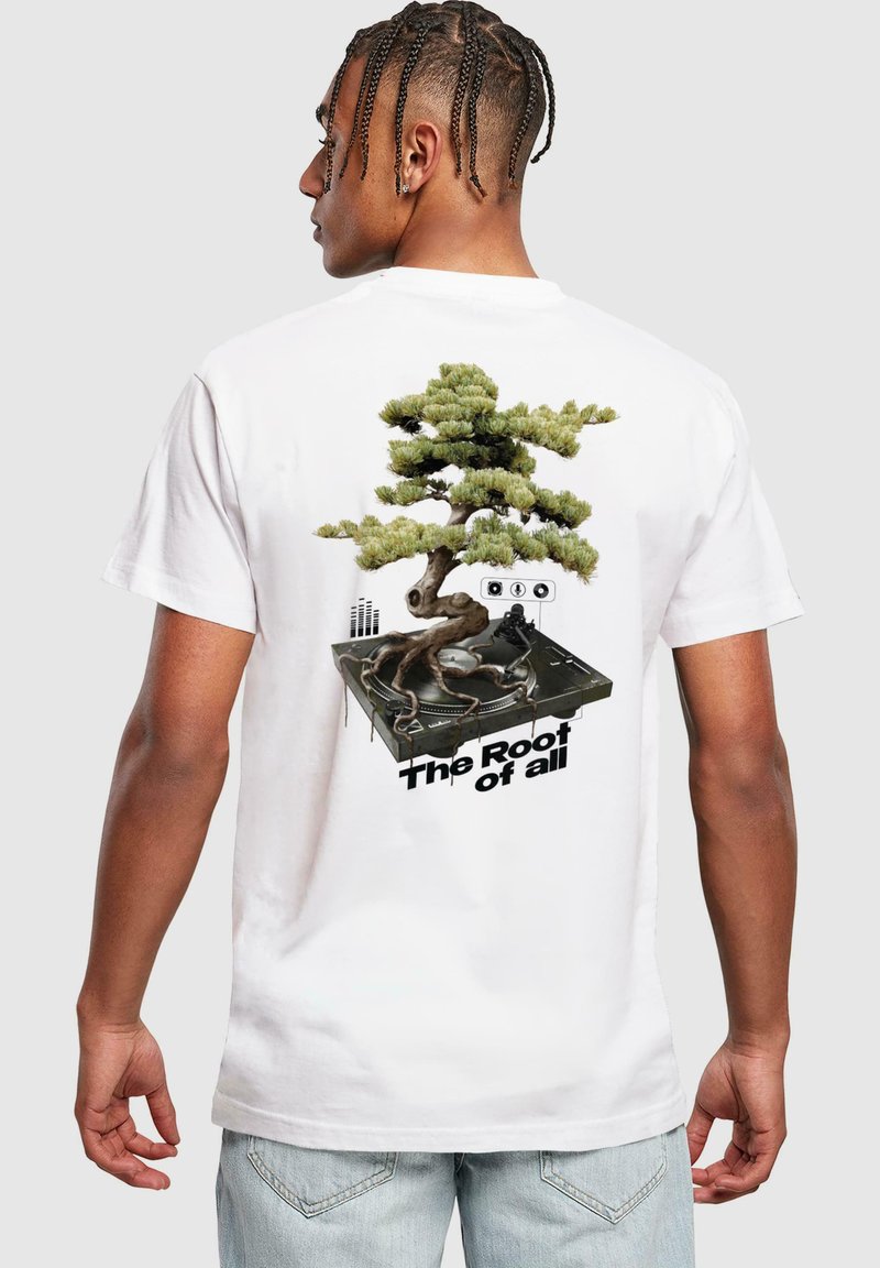 Bela majica z grafiko bonsai drevesa in gramofona ter besedilom "Koreni vsega." Oblikovanje vključuje zelene in črne podrobnosti.