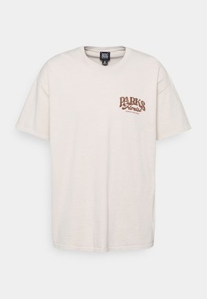 Beżowa koszulka z krótkim rękawem, okrągłym dekoltem i brązowym napisem "Parks Florist Wilmington North Carolina" na lewej piersi.