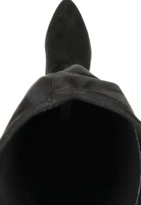 Botte noire à bout pointu avec une texture en daim doux, tige haute et intérieur lisse. La silhouette est élégante et ajustée. Aucune quincaillerie visible.
