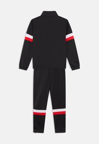 Μαύρη φόρμα από πολυεστέρα, με μακριά μανίκια και παντελόνια που έχουν κόκκινες και λευκές ρίγες στα χέρια και τα πόδια.