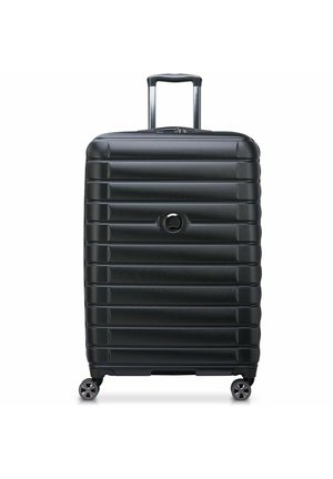 Hard-shell black suitcase with a ribbed design, a telescopic handle, and four spinner wheels. Features a round logo on the front.
